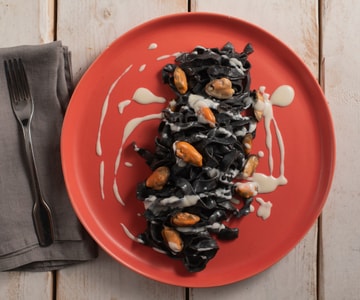 Tagliatelle à l'encre de seiche avec pecorino, moules et lard