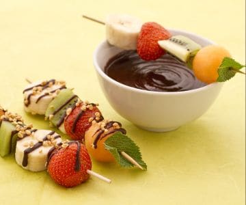 Brochettes de fruits avec sauce au chocolat et éclats de noisettes