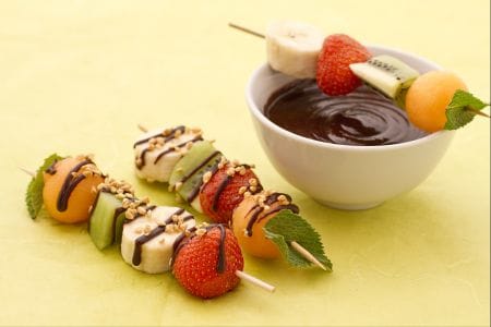 Brochettes de fruits avec sauce au chocolat et éclats de noisettes