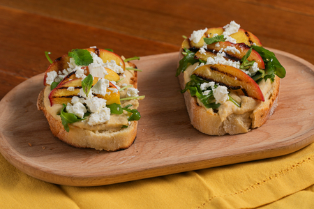 Crostini avec houmous, pêches grillées, feta et roquette