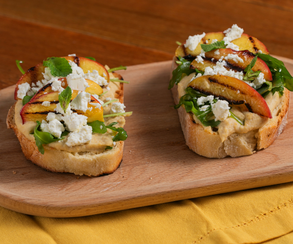 Crostini avec houmous, pêches grillées, feta et roquette