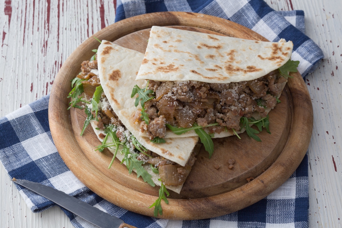 Piadina avec saucisse et oignons mijotés